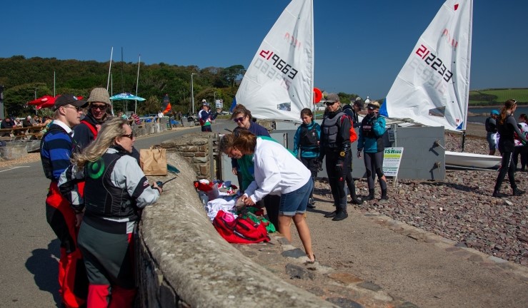 OnBoard Festival volunteers sorting race bibs and looking out to the bay from the sea wall at Dale.