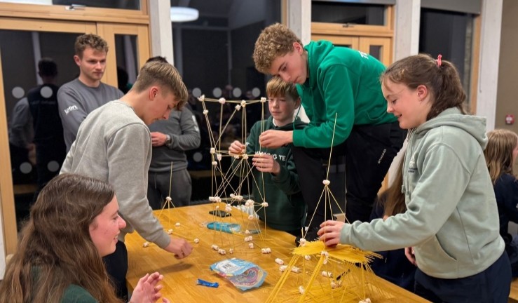 Competition to build the tallest tower out of marshmallows and uncooked spaghetti with team of sailors concentrating on their construction!