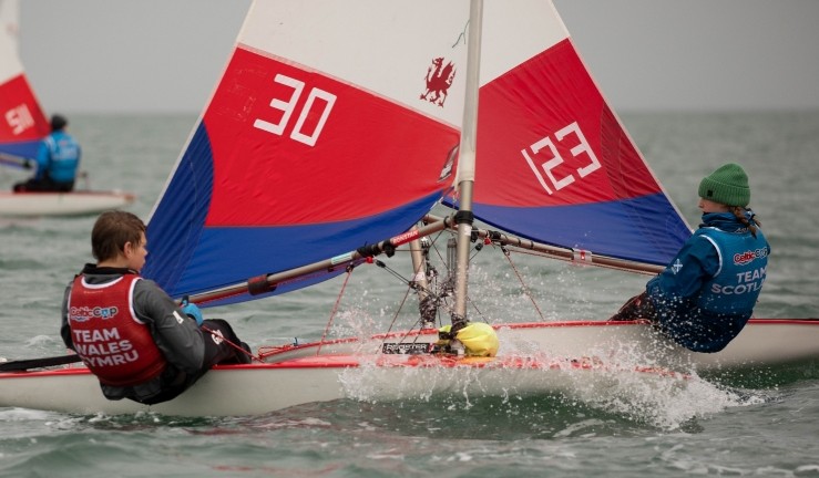 Welsh and Scottish sailor competing in Toppers at the Celtic Cup 2025 with red white and blue sails of each on opposite tacks to make it a symetric butterfly image.