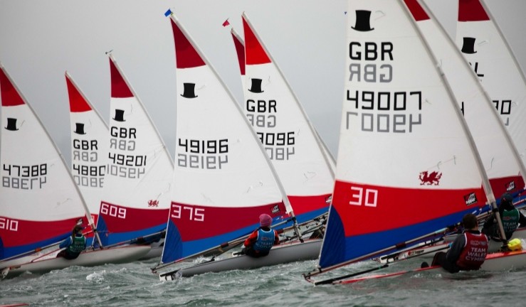Topper sailors racing upwind at the Celtic Cup 2025 wearing  red Welsh, blue Scottish and green N Ireland bibs.