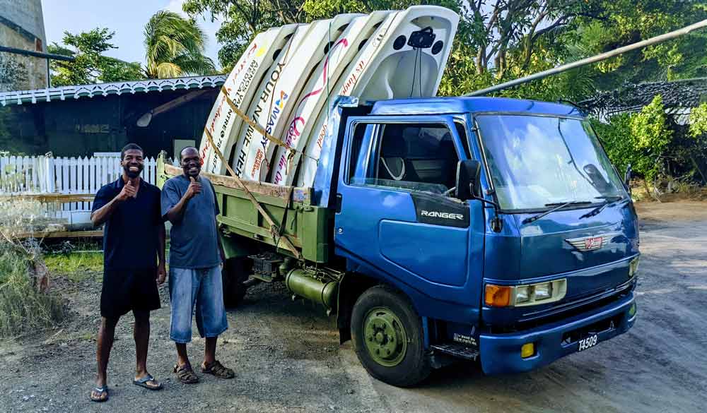 men stood next to a truck with boats on it 