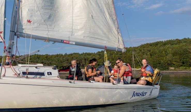 Group of people enjoying sunshine and blue skies on a yacht with SEAS Sailability.