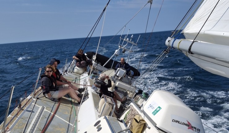RYA CW's Hester Walker sat on deck at sea aboard the Challenge Wales sail training ship on sunny day.