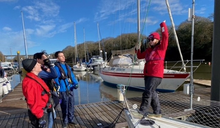 Freya Terry, one of the first recipients of an RYA CW Impact Award, instructing for PPSA on a keelboat to a group standing on a pontoon.