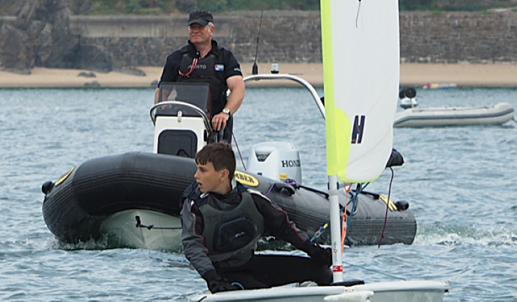 CW Impact Award recipient Richard 'Taff' Owens of PPSA dirving a powerboat and coaching a young sailor.