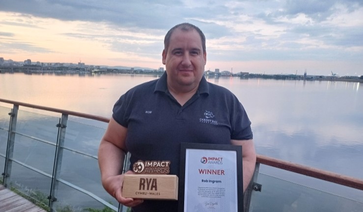 Powerboater Rob Ingram standing next to the water at Cardiff Bay with his RYA CW Impact Award. 