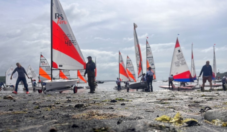 Colourful junior dinghies launching for Welsh Regional Junior Championships 2025 from the beach at Dale.