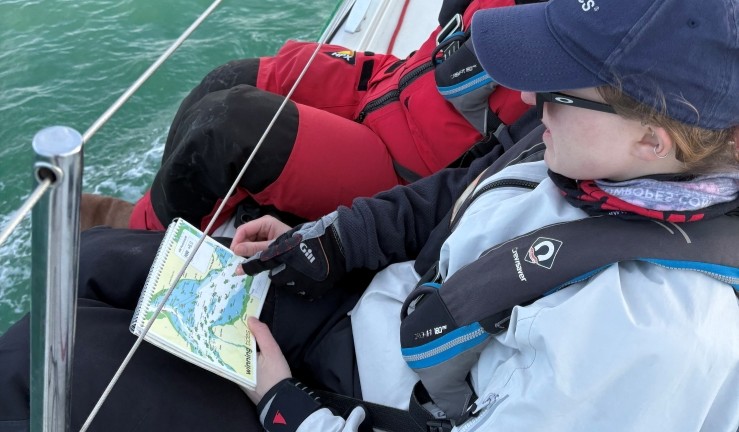 Two crew on the rail of a yacht navigating with chart during BSKA inshore weekend.