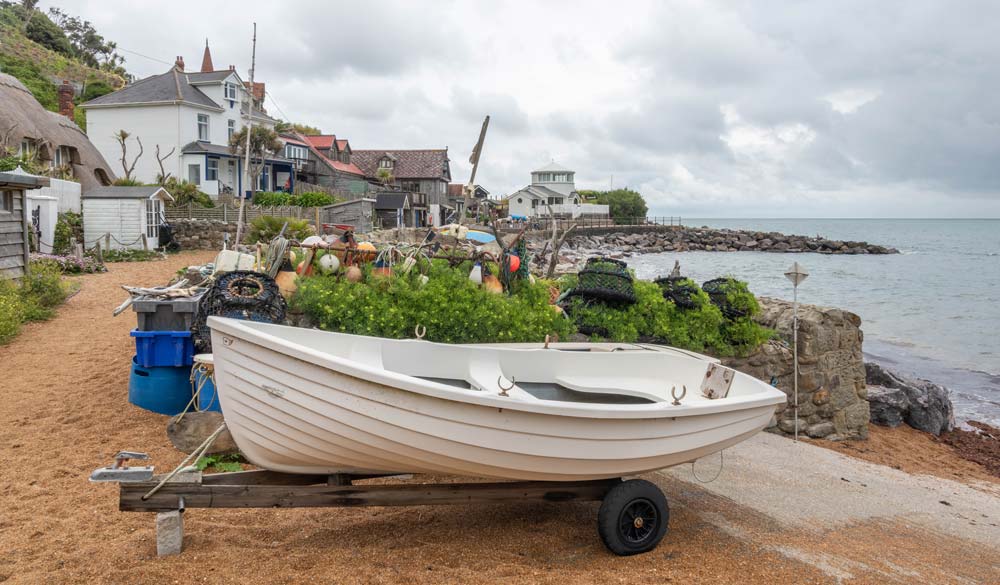 white boat on foreground infront of houses on shore