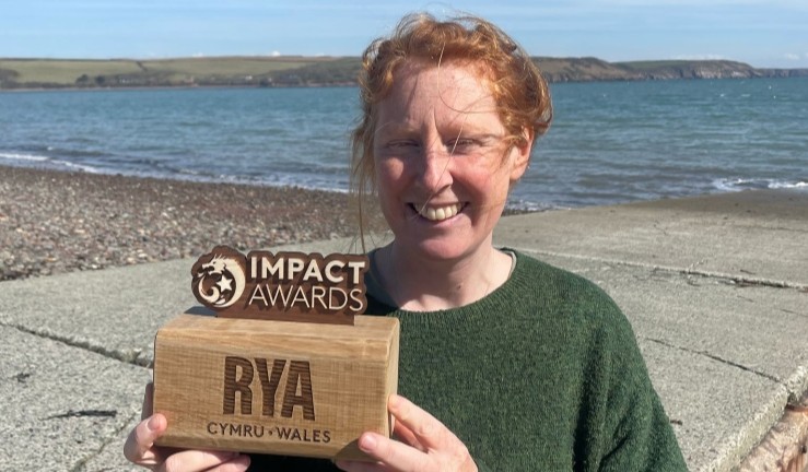Sarah Bagley of Windswept Watersports by the sea with her RYA Cymru Wales Impact Award.