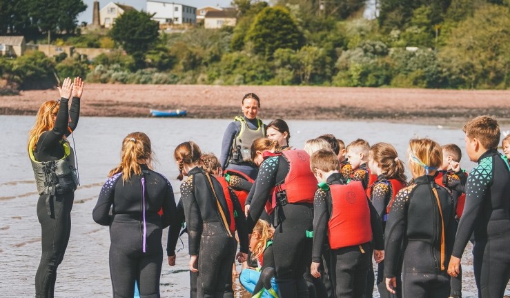 RYA CW Impact Awardee Sarah Bagley of Windswept Watesports teaching a group of children on shore at Dale.