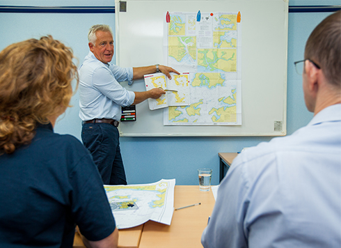 Man stood at board with chart giving a navigation lesson