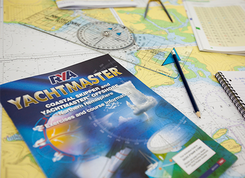 Coastal Skipper Yachtmaster Offshore theory course materials on table with charts and other training materials