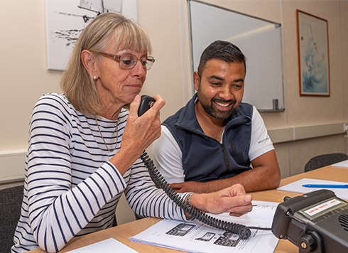 Woman practicing Marine VHF Radio skills on RYA SRC course