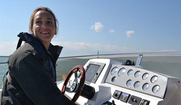 RYA Day Skipper Motor practical course. Woman practicing boat manoeuvres and handling on the helm. 