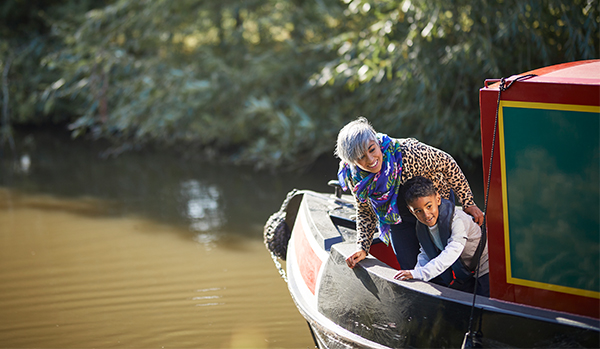 Woman and child stood at bow of canal boat smiling and pointing at something in the water