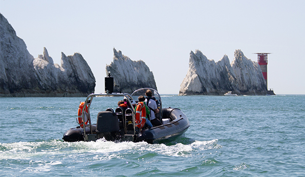 RIB driving away from camera towards the needles, blue sky, sunny day