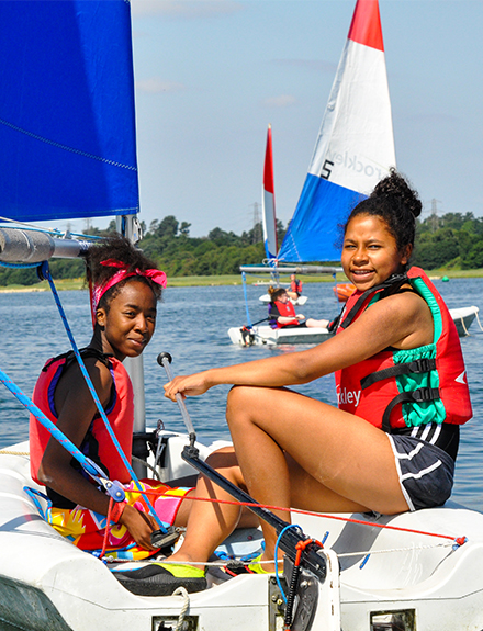 Two girls smiling sailing dinghy