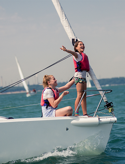two girls at bow of keelboat smiling and laughing