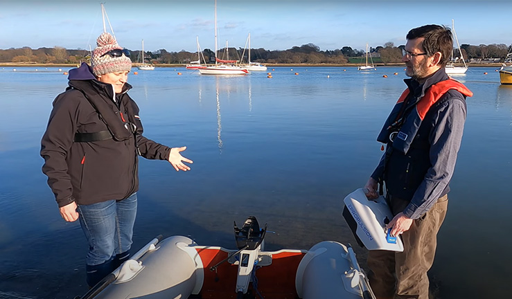 Wide shot of two people talking either side of boat 