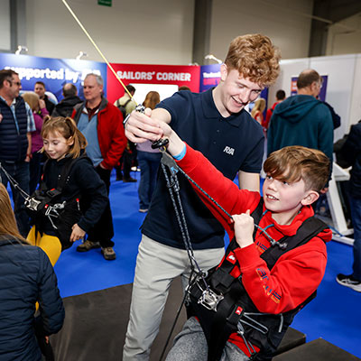 A young boy using the trapeze rig at the dinghy show