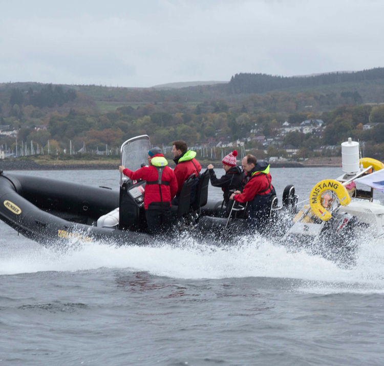 Long shot of group of four sailors on a powerboat with water splashing