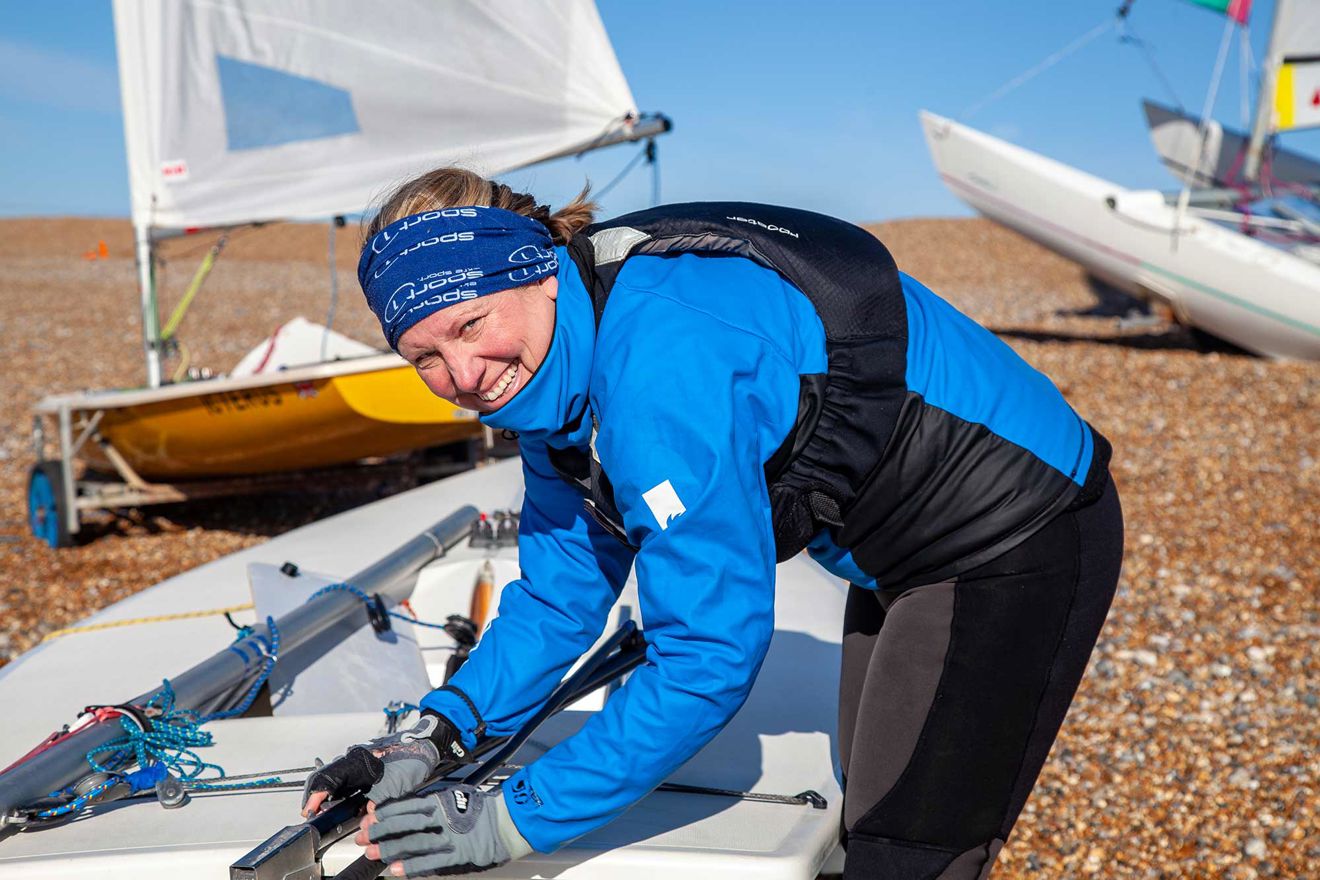 Wide shot of woman smiling next her dinghy 
