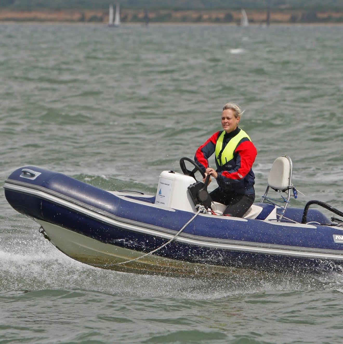 Lady driving a rib on the open water with a life jacket on and kill cord attached