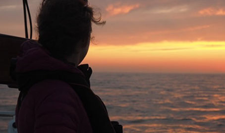 sailor looking out at water during sunset