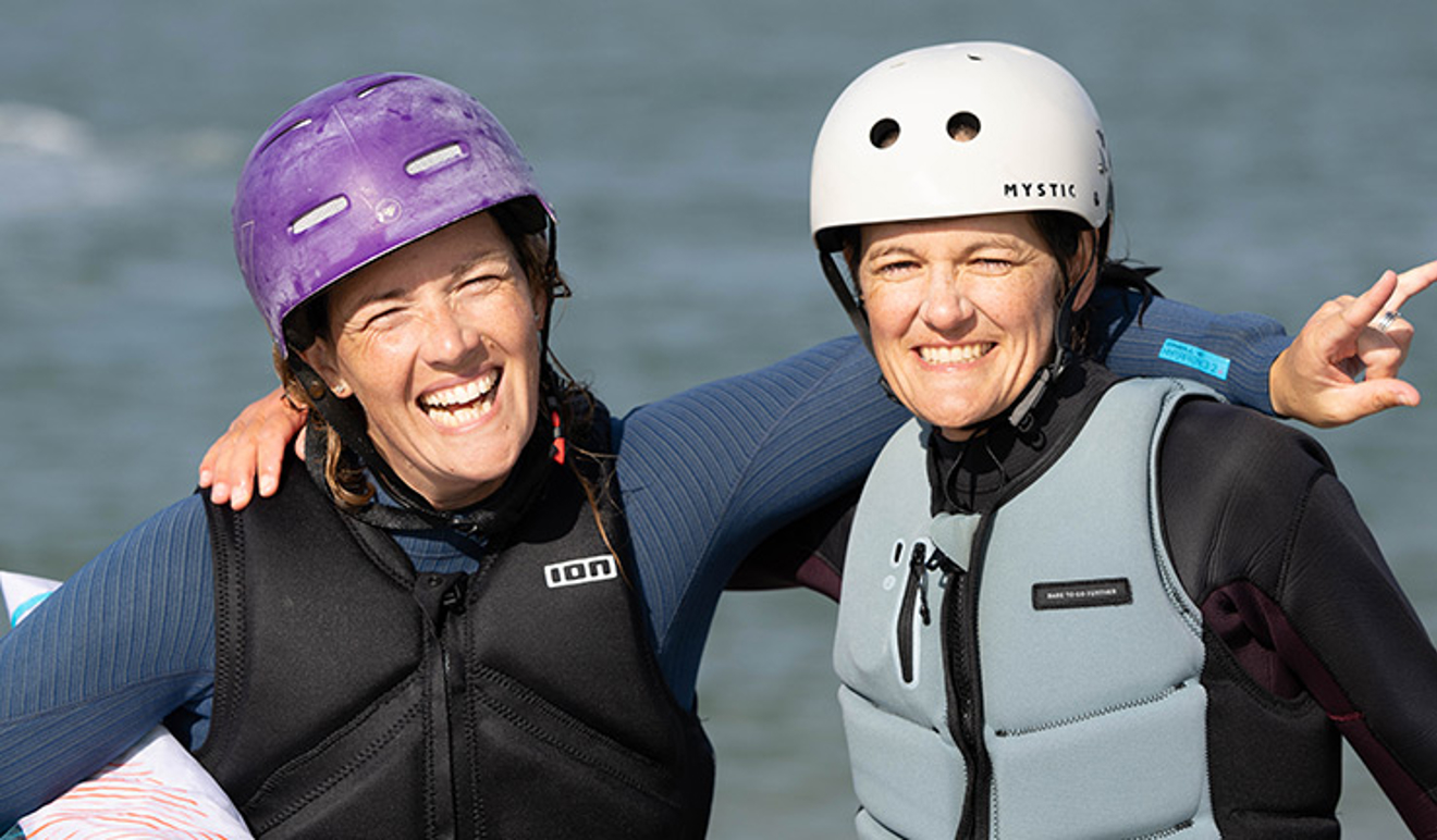 two woman with their arms around each other smiling