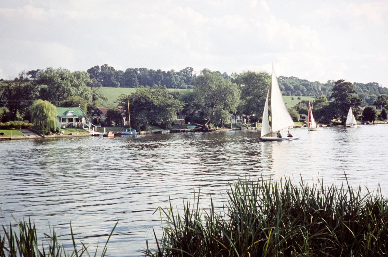 wide shot of a yacht sailing across a country lake