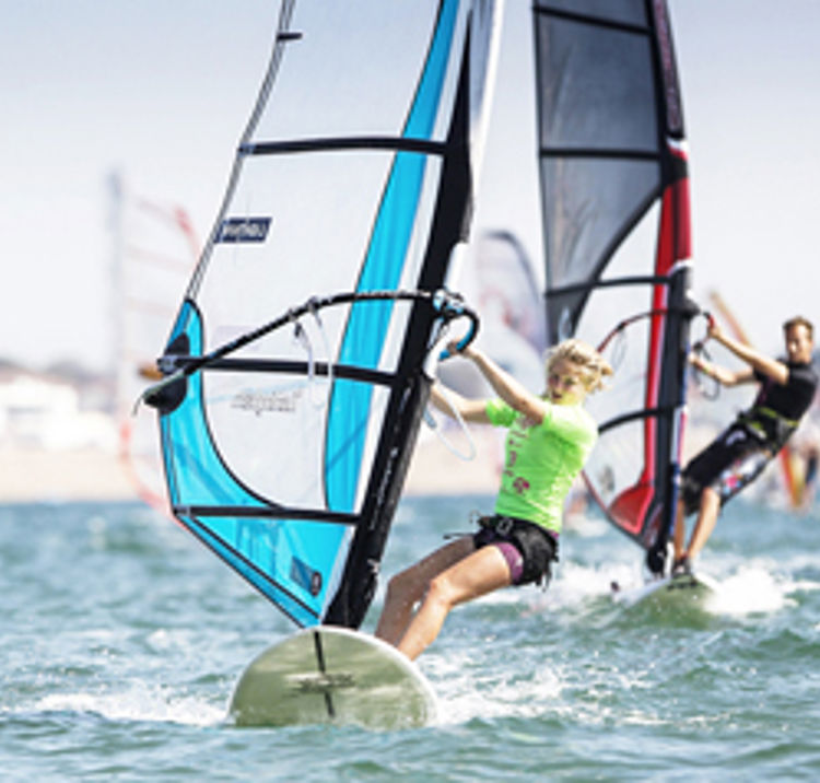 	An image showing two people windsurfing on the water.