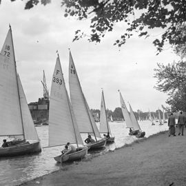 Black and white image of multiple dinghies on the shore