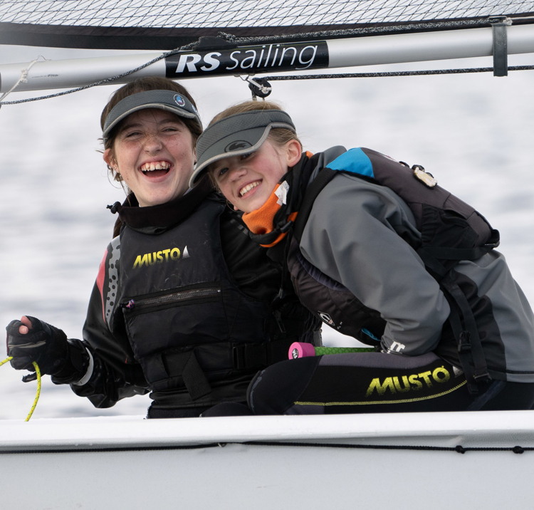 An image of two young girls laughing while sailing the boat