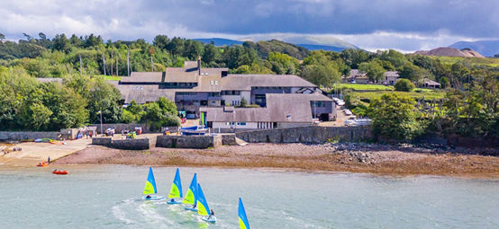 Aerial view over Plas Menai national outdoor centre with training dinghies heading out to sea.
