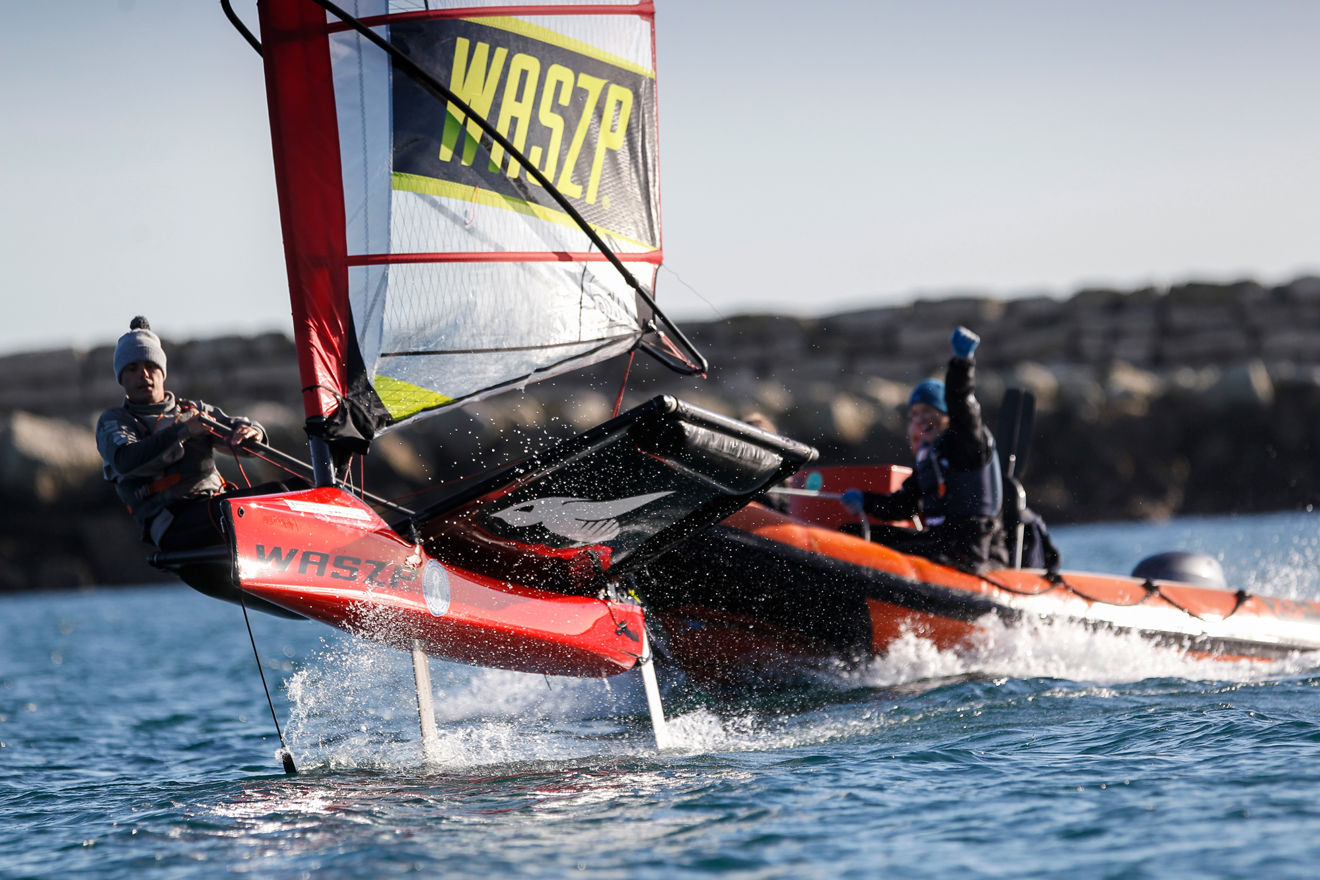 person sailing with a safety boat behind