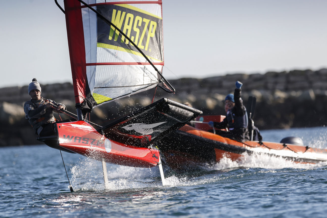 person sailing with a safety boat behind