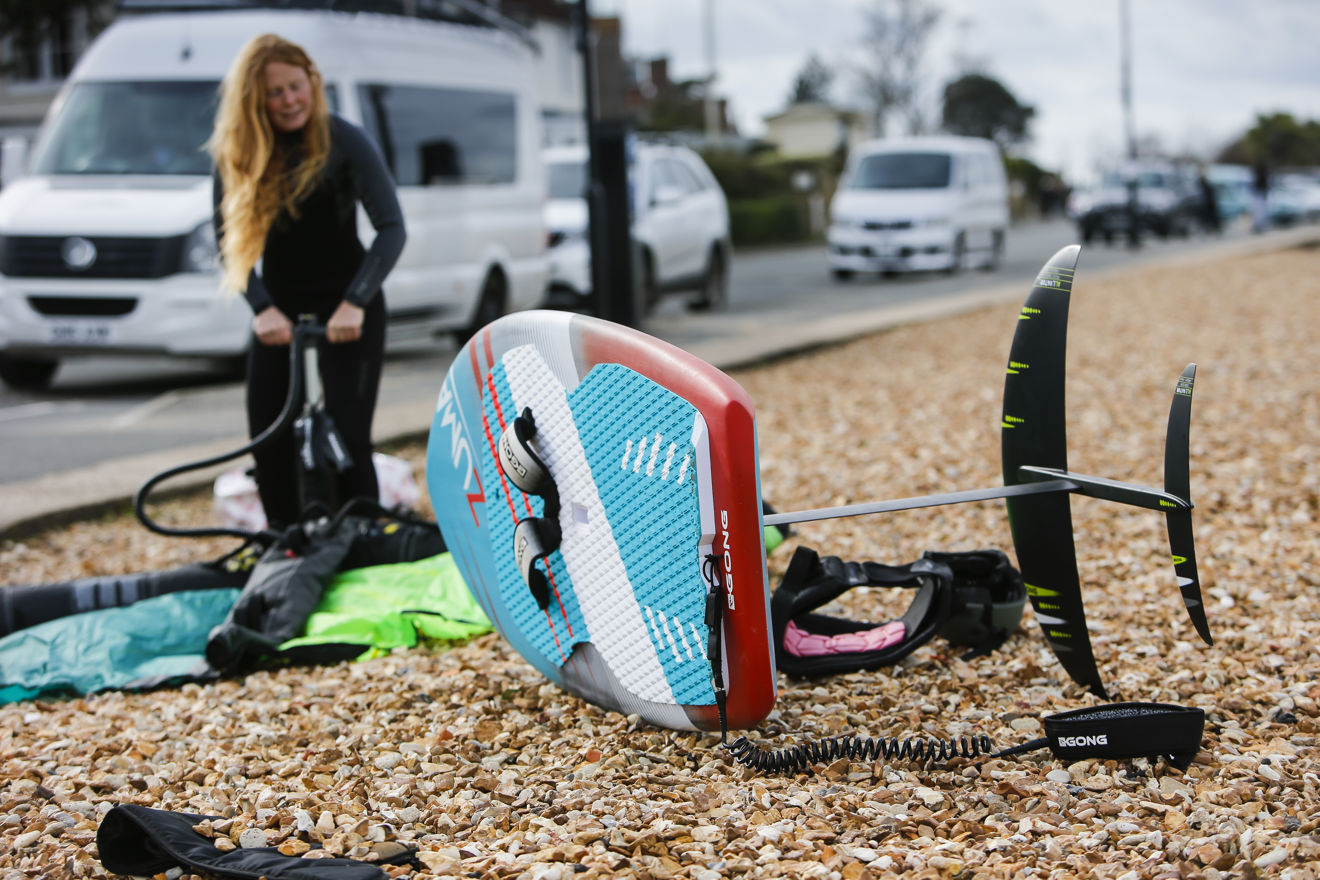 lady pumping up her wing to wingsurf on the shore