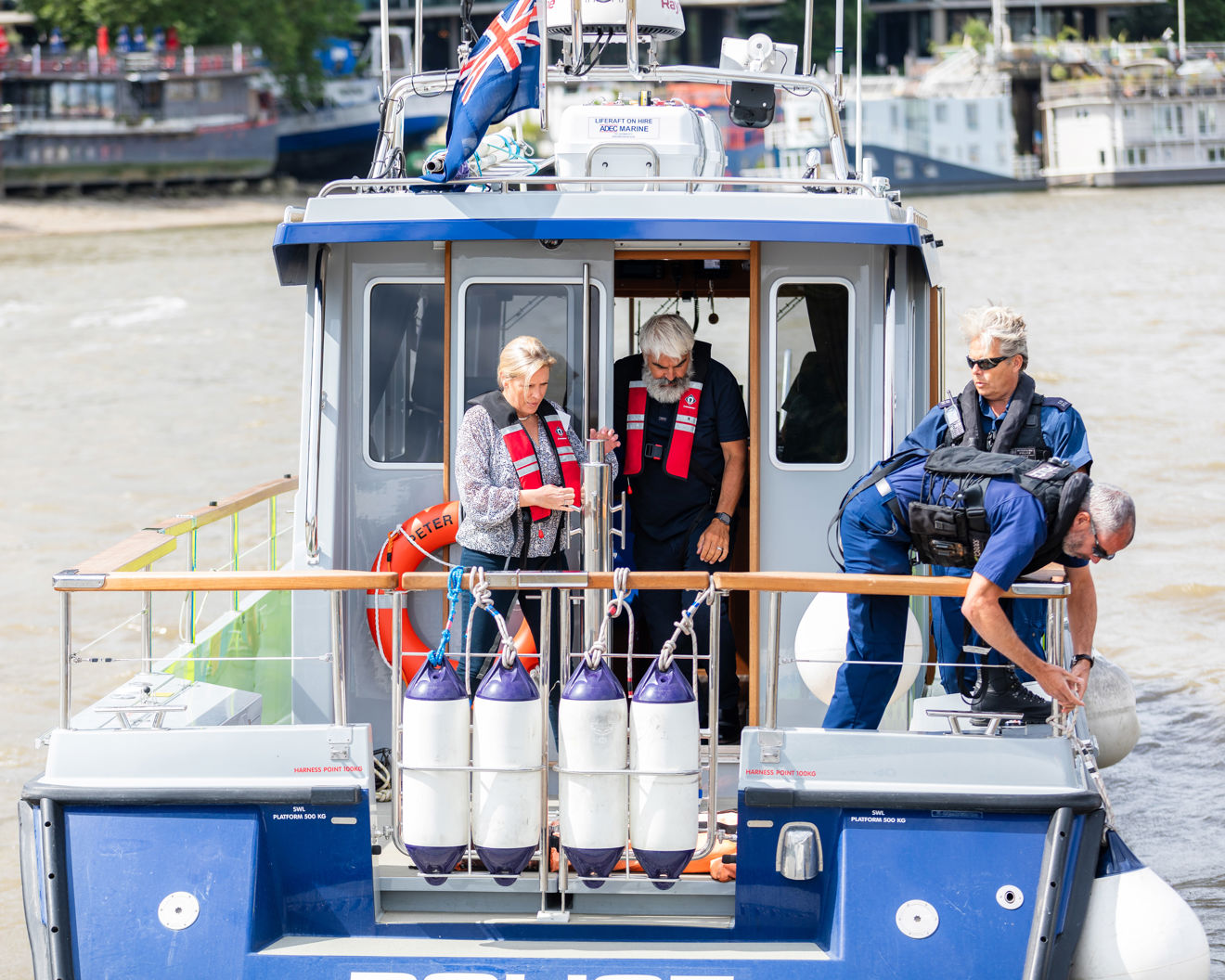 Baroness Vere standing at the back of a motorboat talking with crew