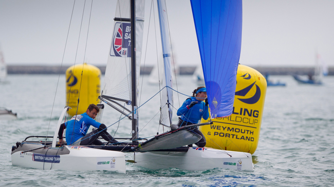 Long shot of two sailors on a multihull with spinnaker