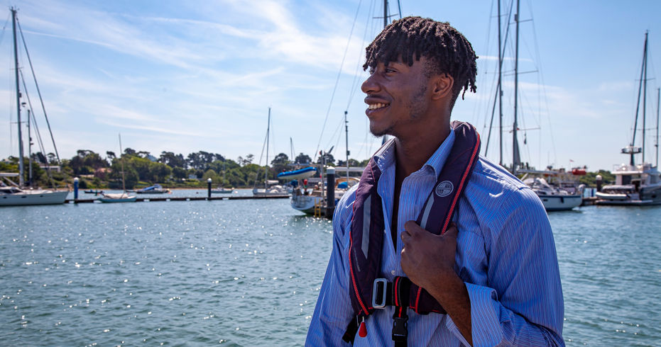 Young man wearing a life jacket and looking out at the water
