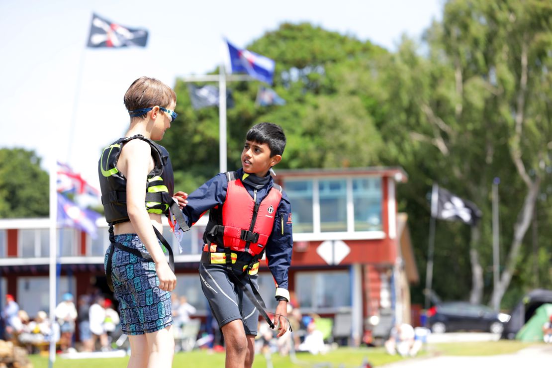two young children on shore talking at a sailing event
