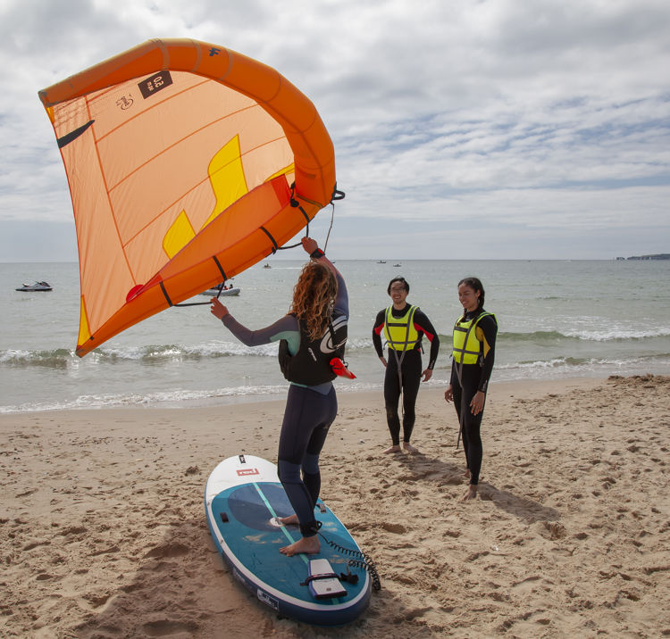 people learning how to wingsurf from an instructor on the beach