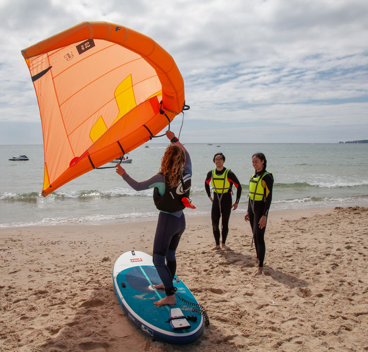 people learning how to wingsurf from an instructor on the beach