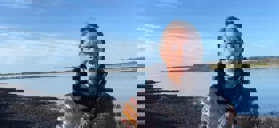 Sarah McGovern, RYA CW Chief Operation Officer, next to the water on Anglesey on a sunny winter day.