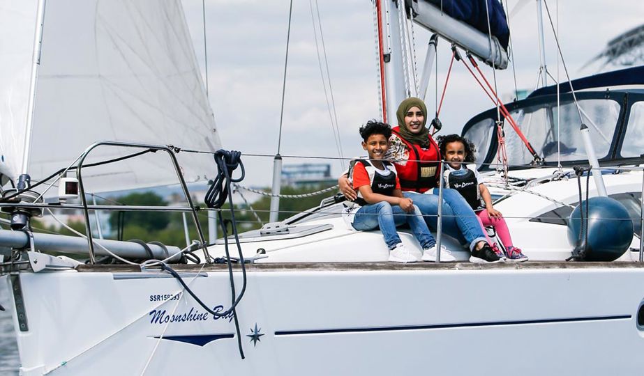 family sat on the bow of a sailing yacht, mother and two young children