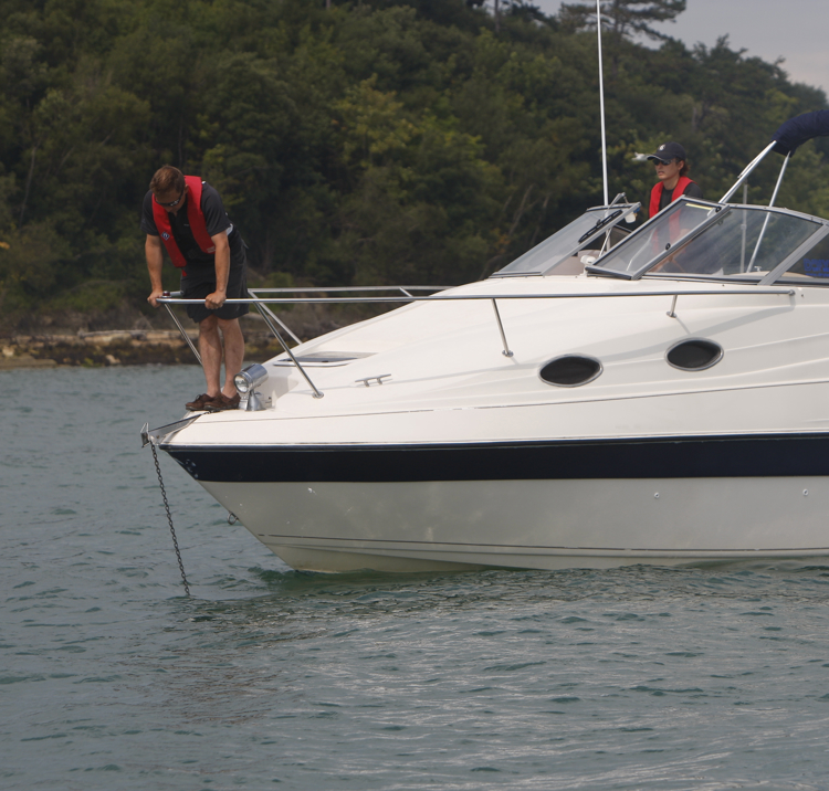 Man stood over bow trying to anchor with care