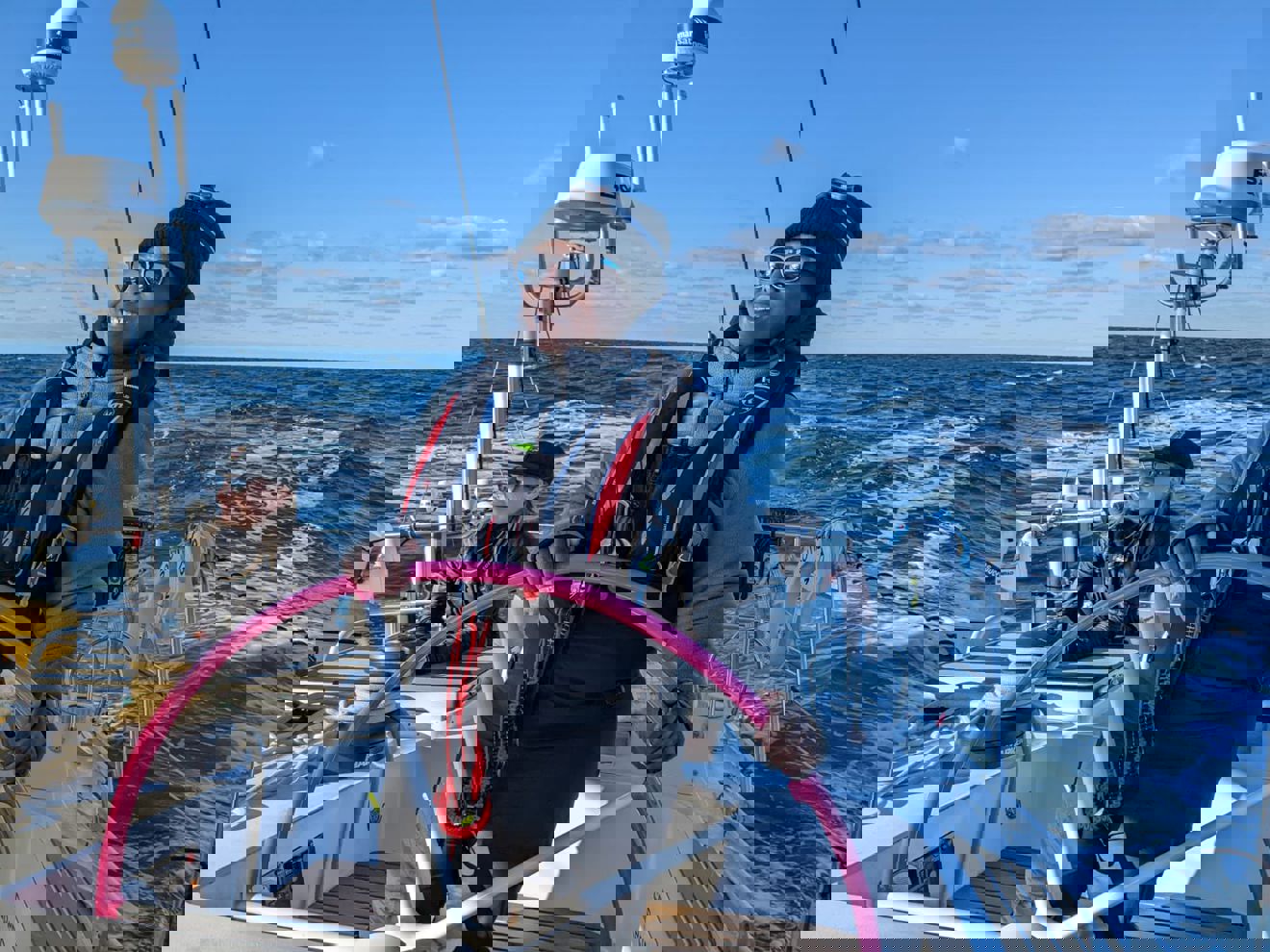 Dramatic shot of woman steering yacht on the open ocean, she is smiling