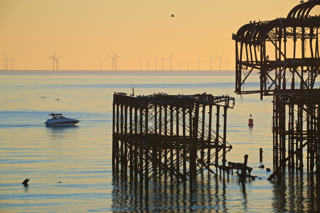 A boat sailing past Brighton peer at sunset