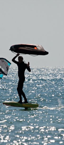 a silhouette of two wing surfers travelling through sparkling water
